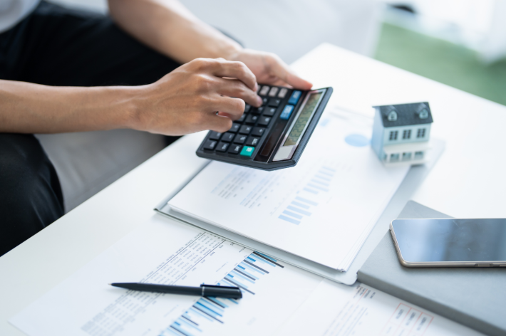 Homebuyer calculating mortgage affordability with calculator, financial documents and house model - Salem Oregon home buying guide