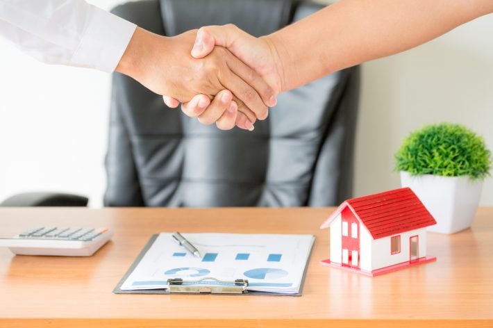 Side view hands of agent and client shaking hands after signed contract buy new apartment.